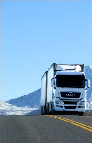 Premium enclosed double-trailer car carrier navigating snowy mountain terrain for secure nationwide winter vehicle relocation.